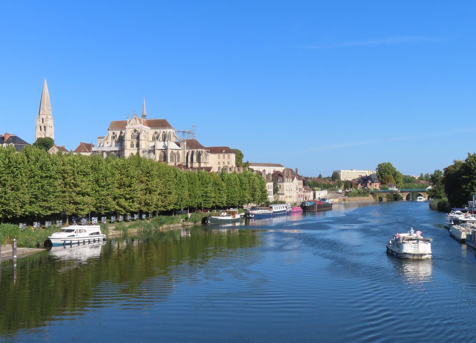 Boats moored on the Yonne at Auxerre below the cathedral, the Burgundy town where the Canal du Nivernais ends — a gateway for affordable barge cruises in France